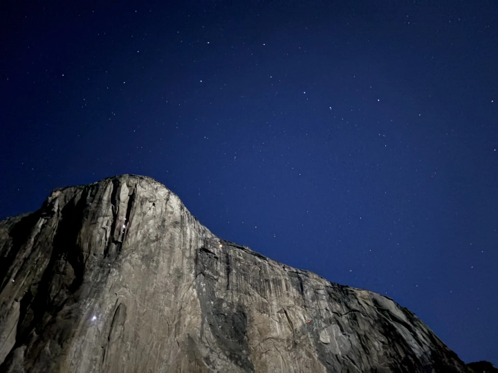 The Big Dipper rises over El Capitan. Tiny dots of light on El Capitan white and orange lights reveal the location of climbers at night.